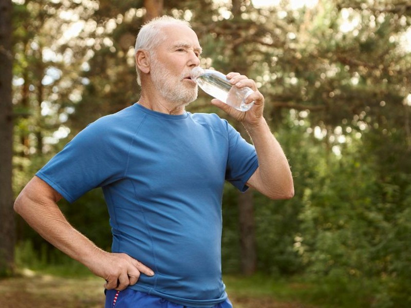 Hydration Reminders for Elderly: Small Habit, Big Impact Senior man drinking water from a bottle outdoors after activity, illustrating why hydration reminders for elderly adults matter even during exercise.