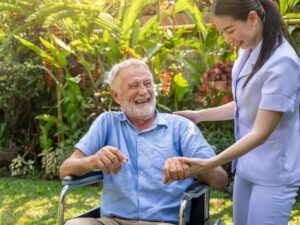 Caregiver holding the hand of a laughing senior in a wheelchair, showing dignity in personal care