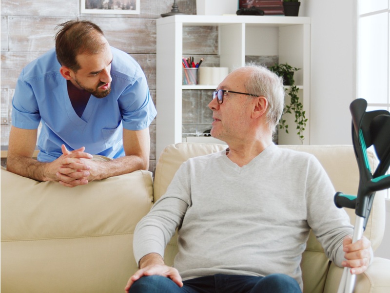 Assisted Living Transition Support: A Family Guide Nurse talking with a senior who holds a crutch, giving assisted living transition support