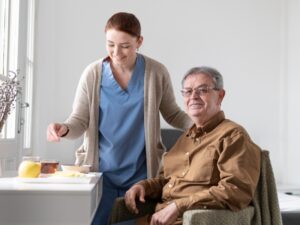 Caregiver serving tea and fruit to a smiling senior, a simple form of assisted living transition support