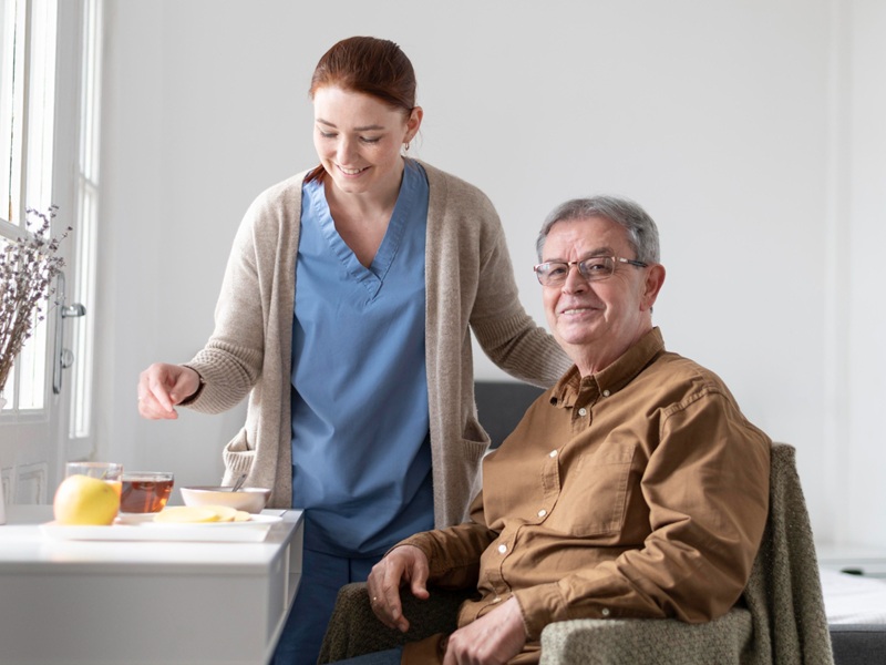 Assisted Living Transition Support: A Family Guide Caregiver serving tea and fruit to a smiling senior, a simple form of assisted living transition support