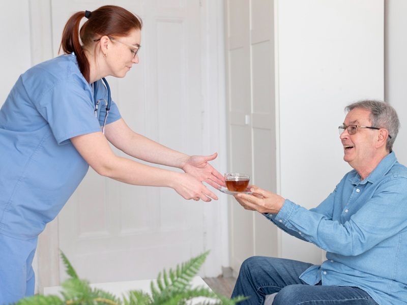 Dignity in Personal Care: Respectful Help for Seniors Nurse handing a cup of tea to a smiling senior, a gentle example of dignity in personal care