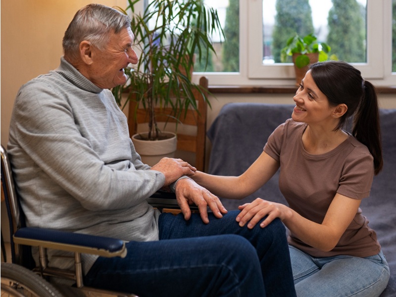 Assisted Living Transition Support: A Family Guide Caregiver smiling with a senior in a wheelchair, offering assisted living transition support at home