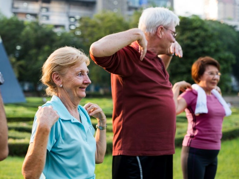 Engaging Activities for Elderly: Ideas for Quiet Afternoons Smiling senior man painting at a table with colorful paints, a creative example of engaging activities for elderly loved ones who enjoy hands on hobbies.